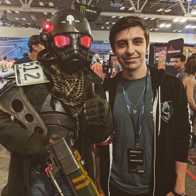 shroud wearing black jacket with grey tee with a person who is wearing gas mask. 